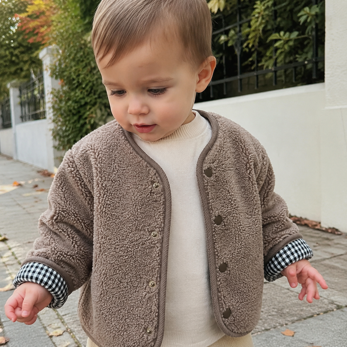 Toddler wearing the light coffee sherpa side of the reversible gingham jacket outdoors