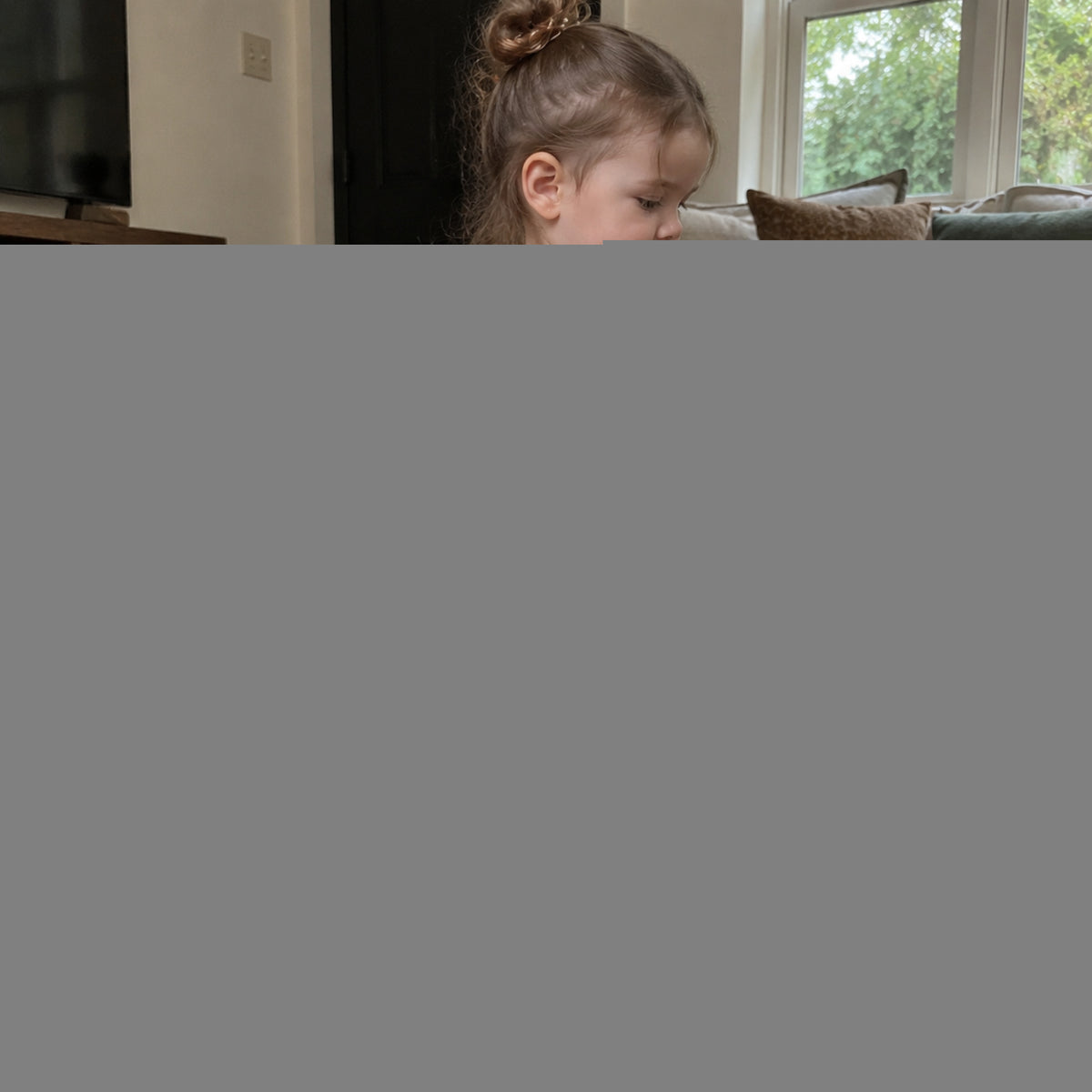 Toddler wearing navy polka dot pants and cream layered ruffle top at home