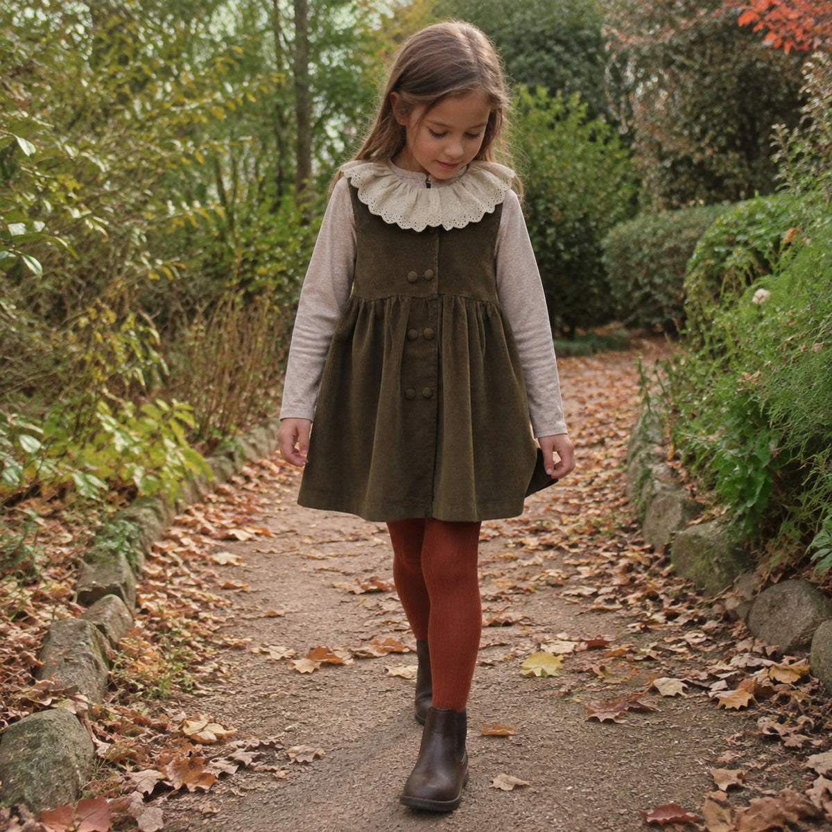 Older girl wearing the olive corduroy pinafore with rust tights on a fall path