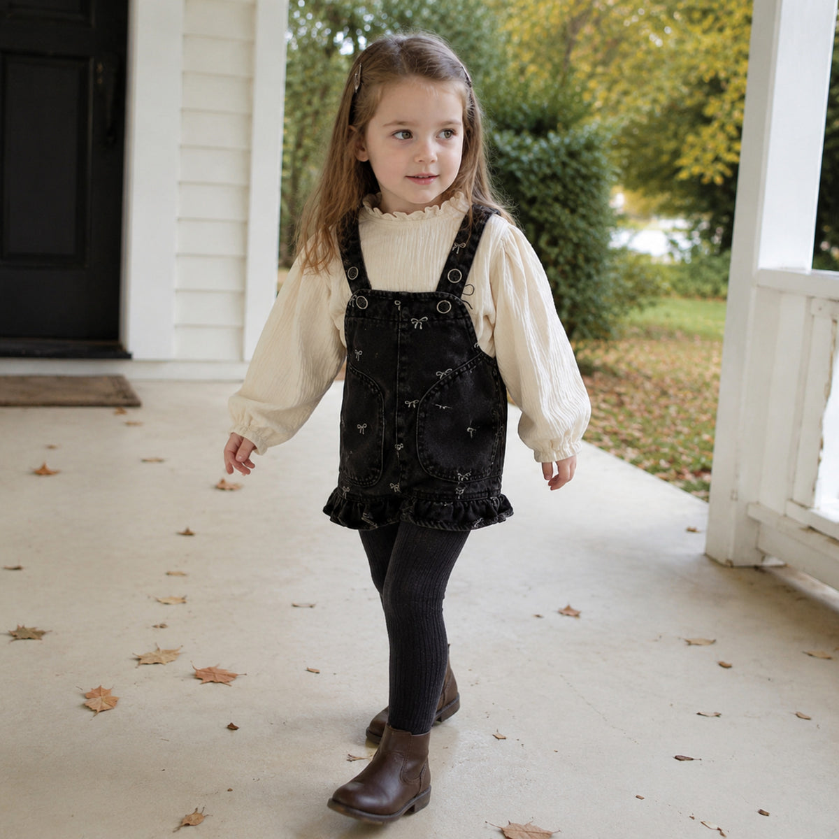 Girl wearing the ivory lantern-sleeve blouse and black denim romper in fall
