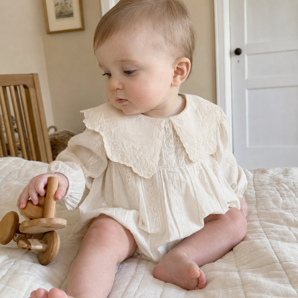 Baby wearing the ivory embroidered collar bubble romper at home