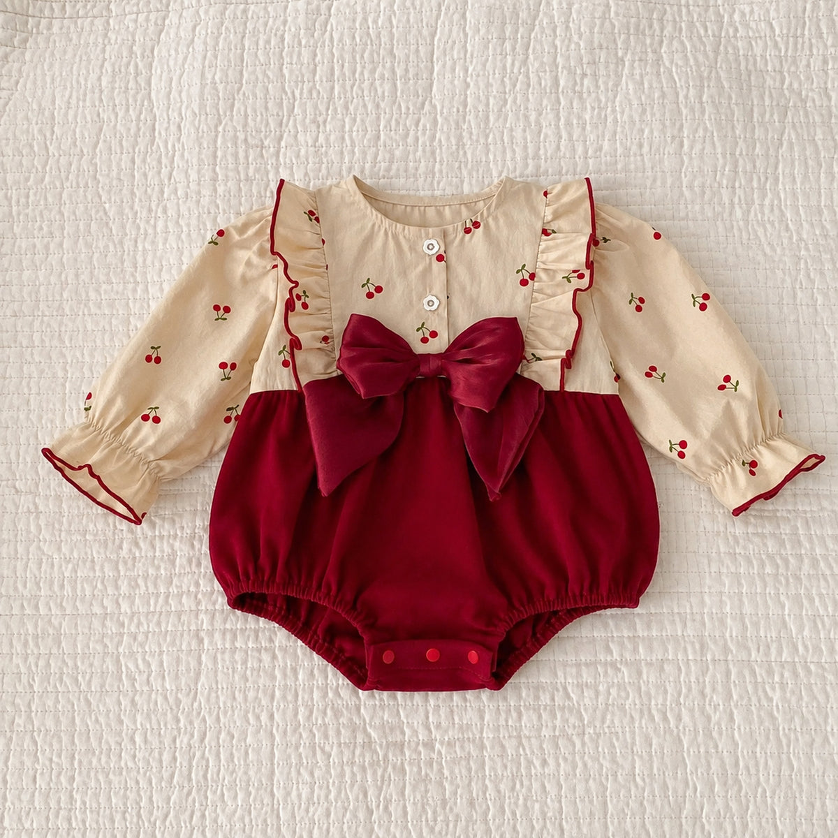 Baby burgundy velvet romper with cherry print long sleeves and large bow - flat lay full product view