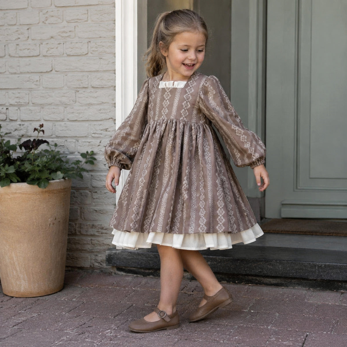 Preschool girl wearing the taupe square neck dress on a home porch