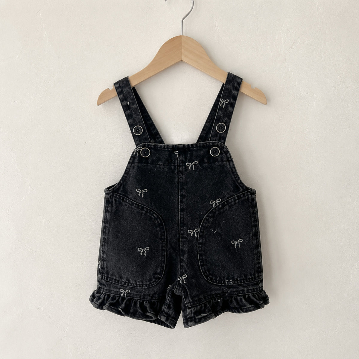 Black bow-print denim suspender shorts romper with ruffled leg hems