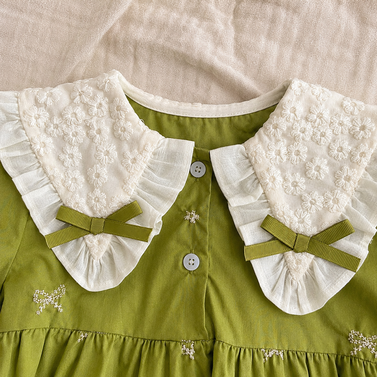 Ivory daisy embroidered ruffle collar and green ribbon detail