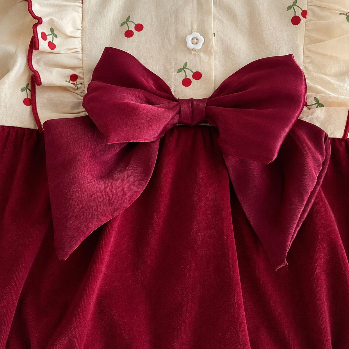 Baby burgundy velvet romper with cherry print long sleeves and large bow - fabric and trim close-up