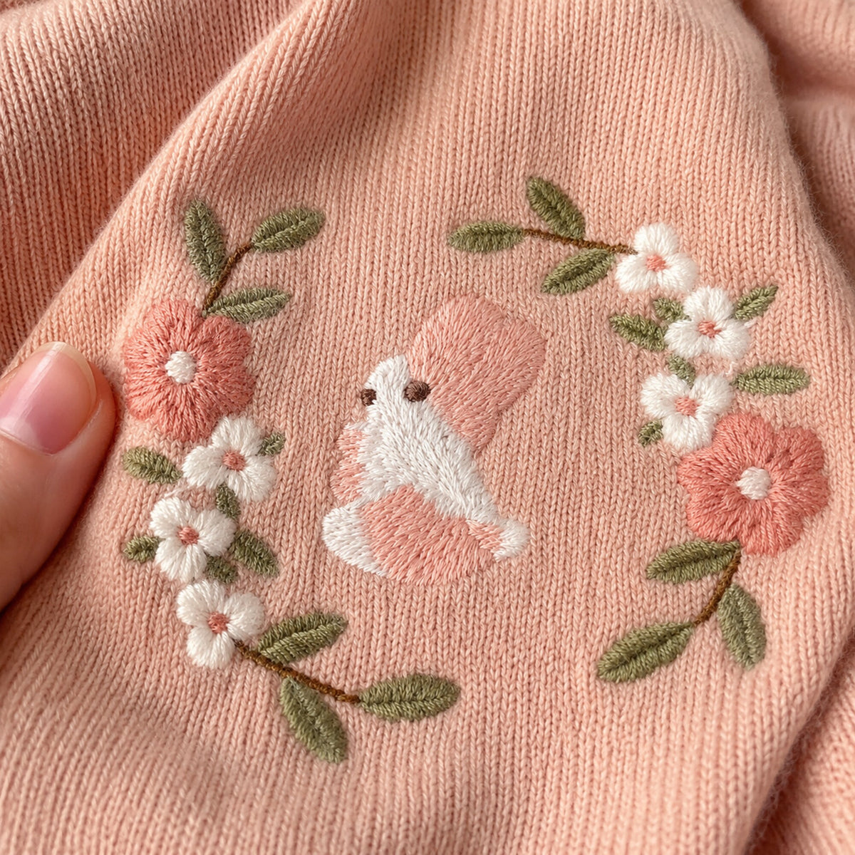 Close-up of the floral bunny embroidery on the dusty pink sweater