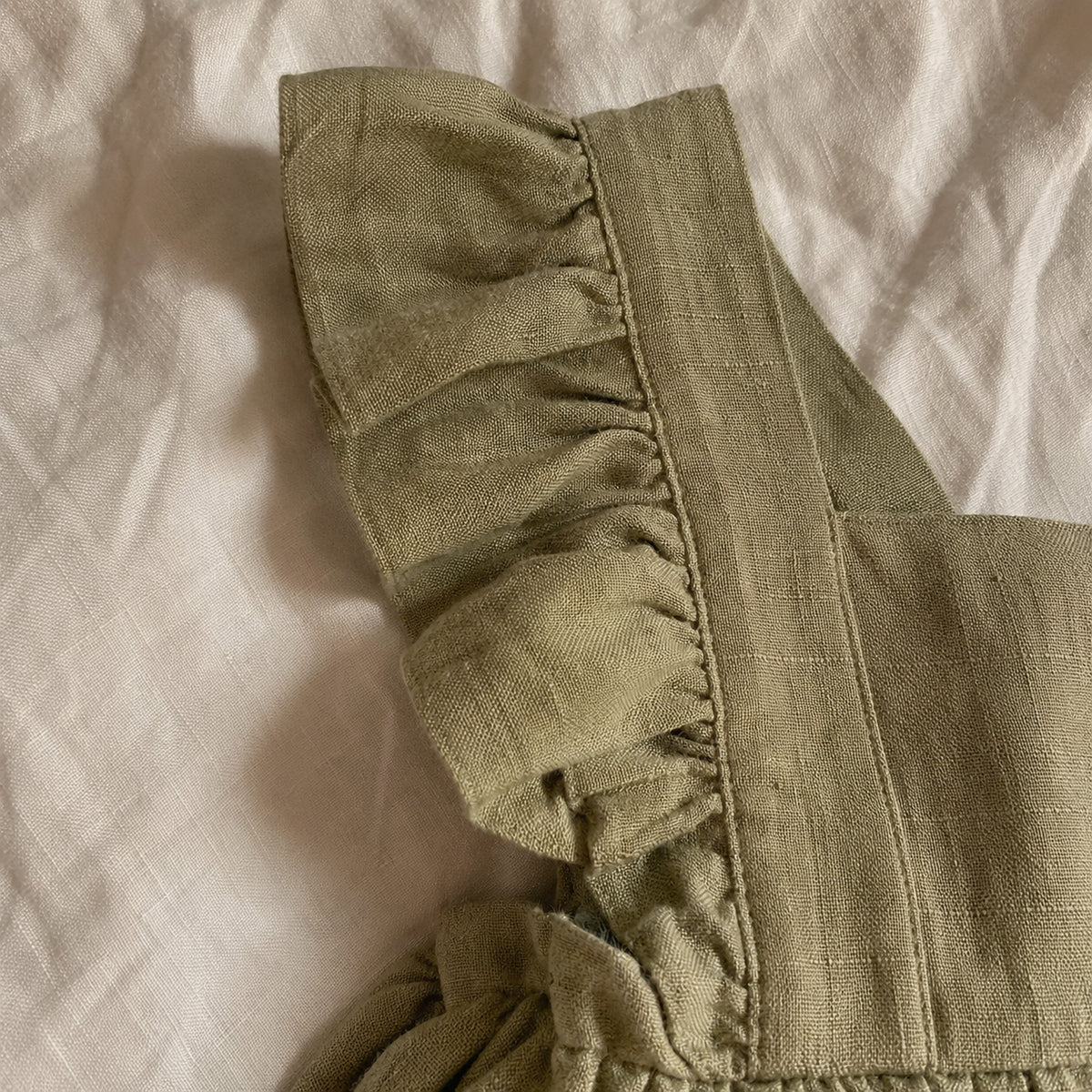 Sage linen pinafore ruffle strap close up
