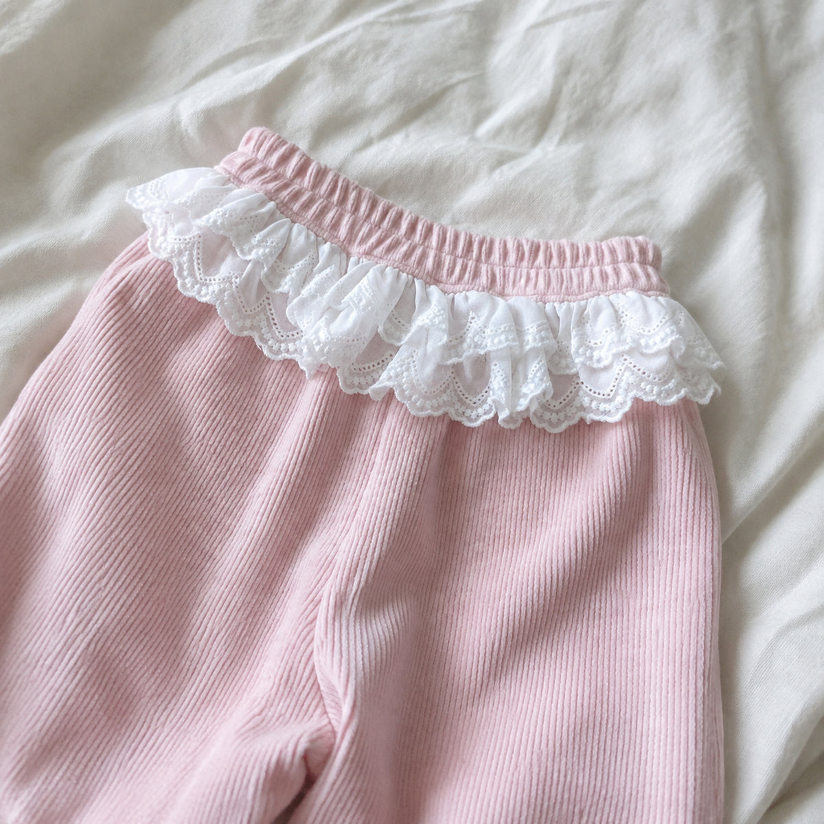 Close-up of the pink pants elastic waist and white eyelet lace ruffle