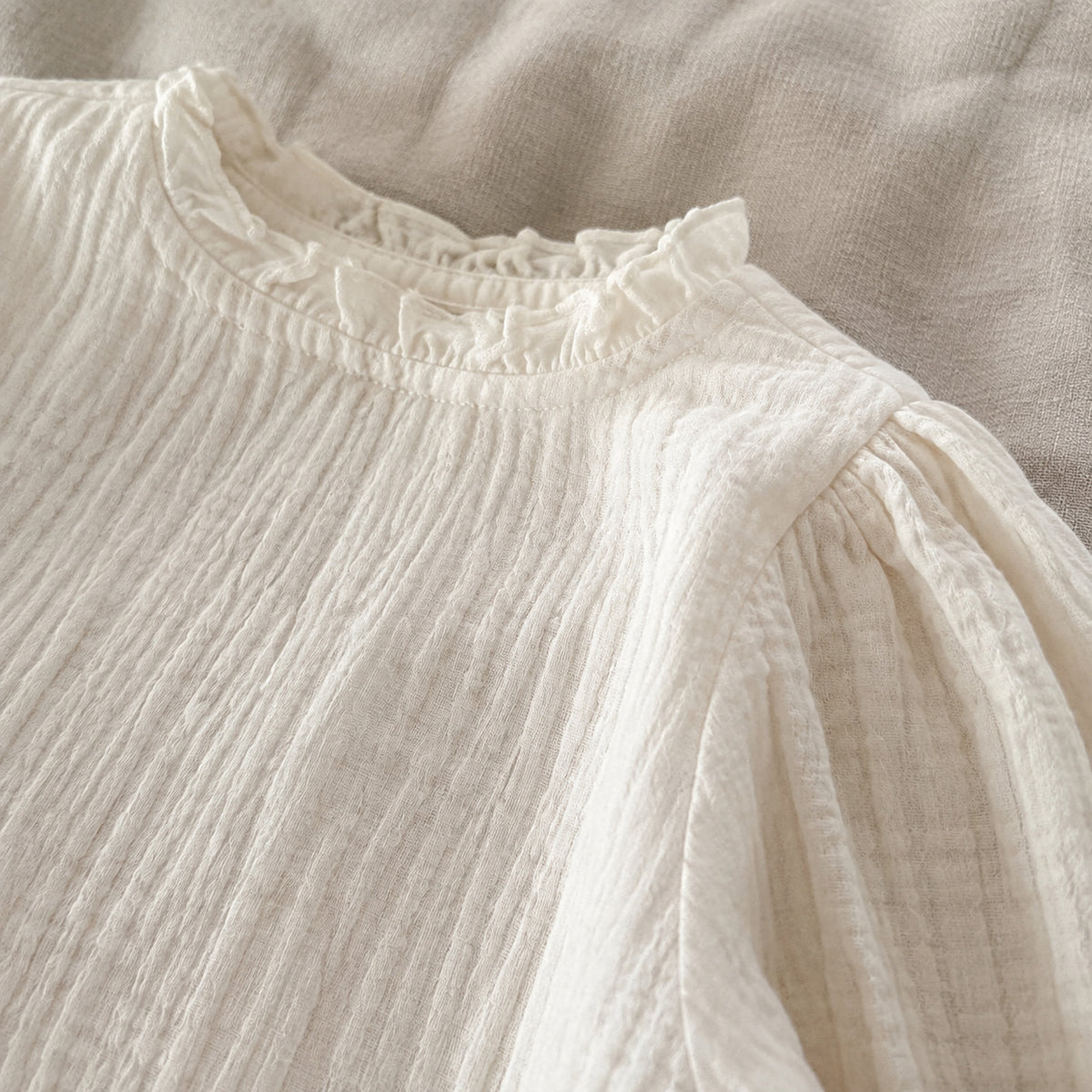 Close-up of the ivory blouse ruffle collar and textured cotton weave