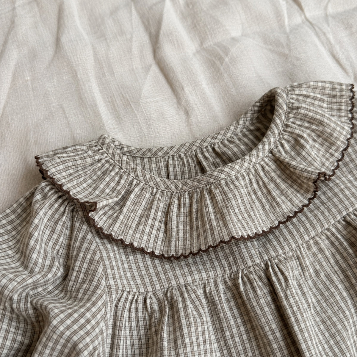 Close-up of brown gingham double ruffle collar with dark scalloped edging