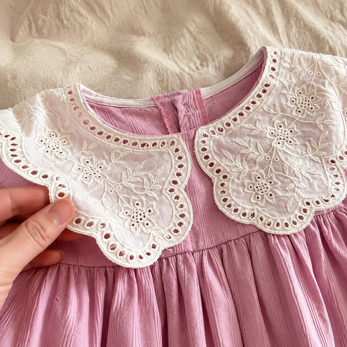 Close-up of the embroidered cream scalloped lace collar