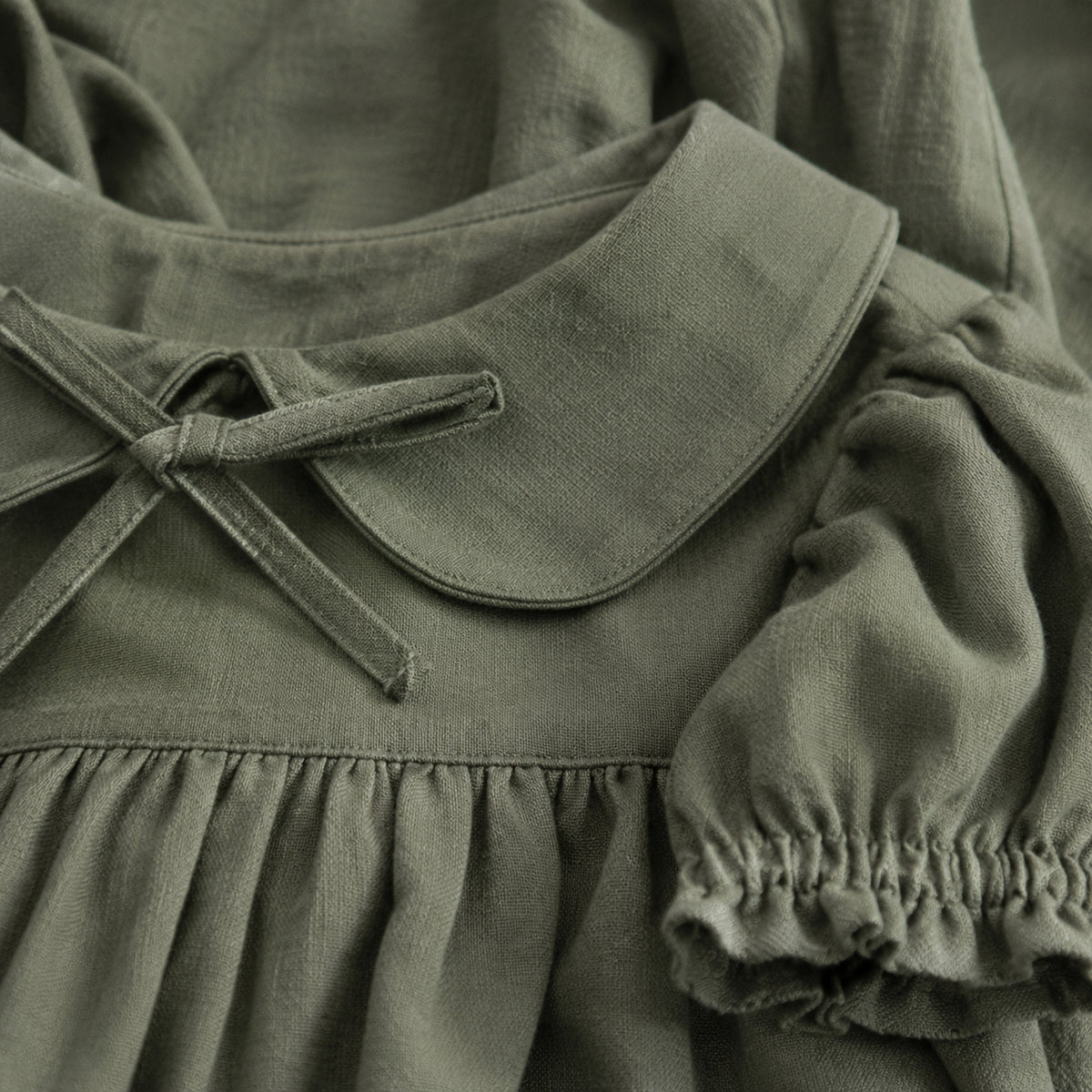 Close-up of the gray-green dress double collar, neckline tie and ruffle cuff