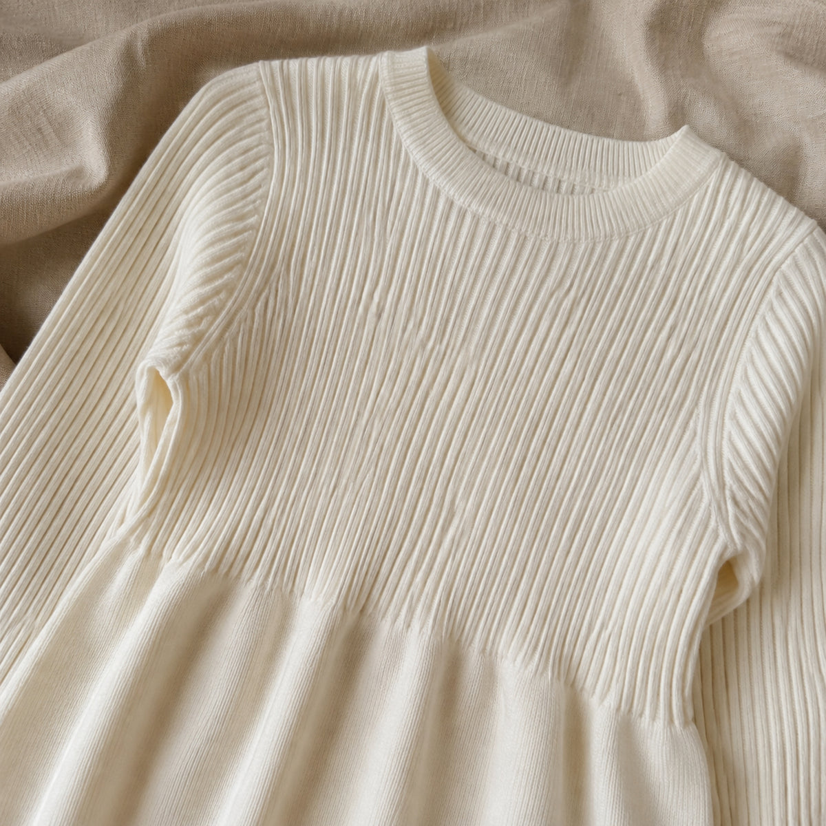 Close-up of ivory ribbed neckline, knit bodice and high gathered waist seam