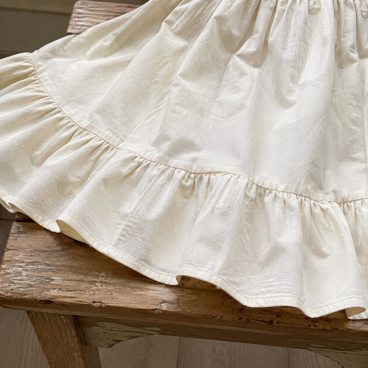 Close-up of broad ruffled hem and linen-look texture on ivory maxi dress