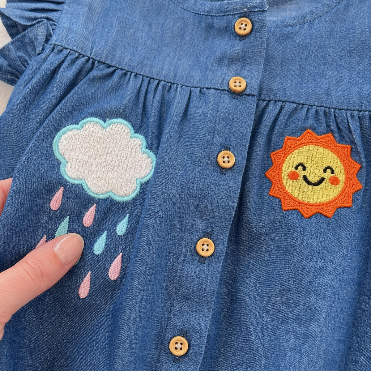 Close-up of rain cloud and smiling sun appliqués