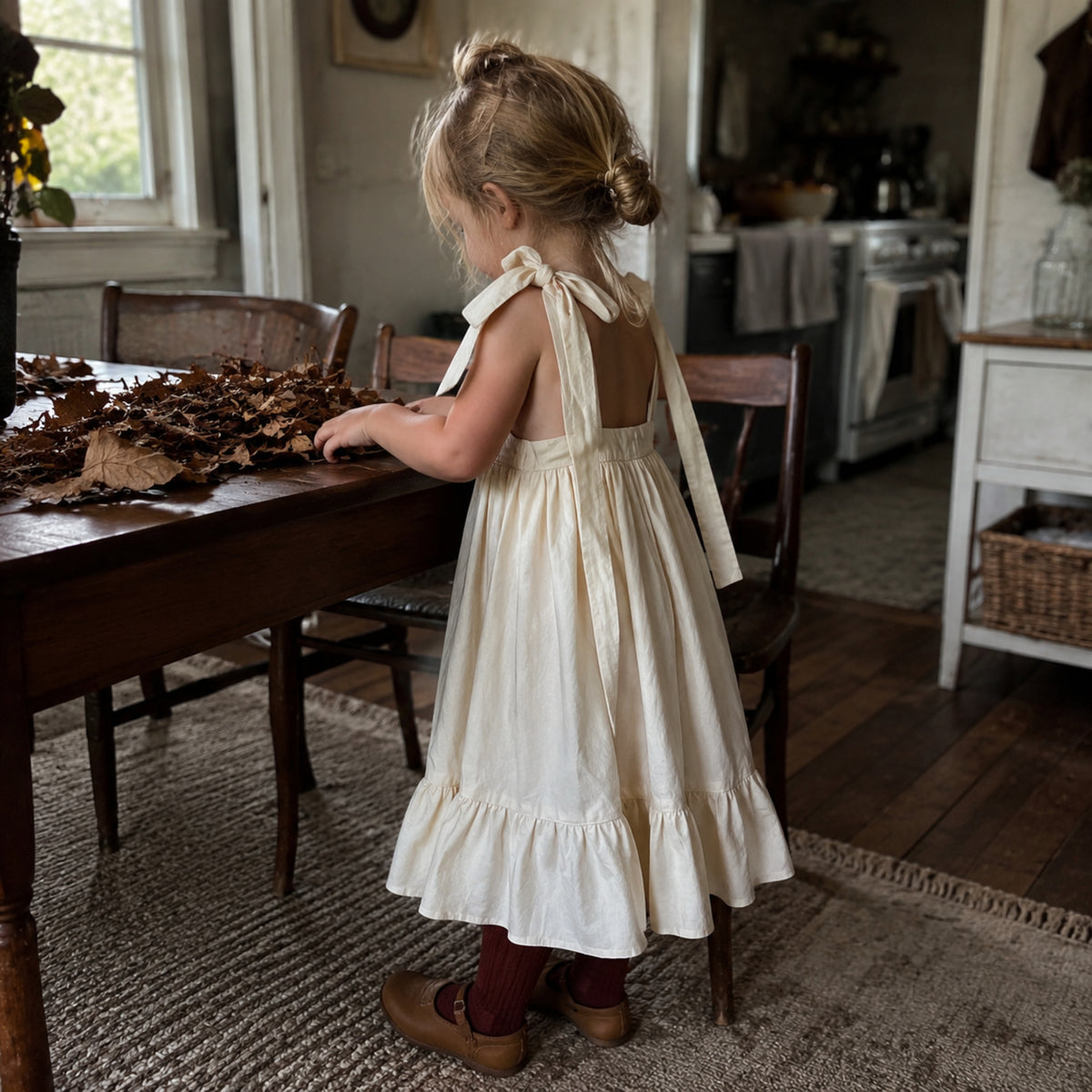 Girl wearing ivory open-back dress with burgundy tights during an autumn craft