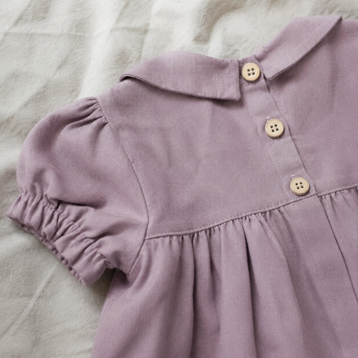 Close-up of the dusty mauve dress back buttons and puff sleeve