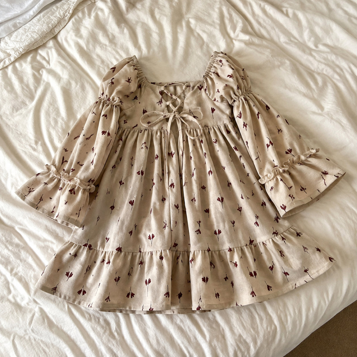 Beige floral girls dress laid naturally on a bed