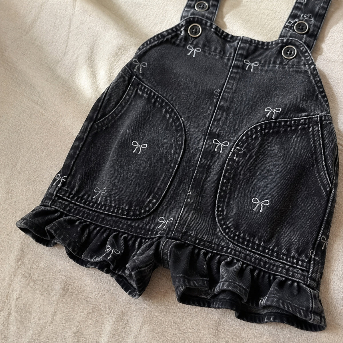 Close-up of the black denim romper separate short legs and ruffled hems
