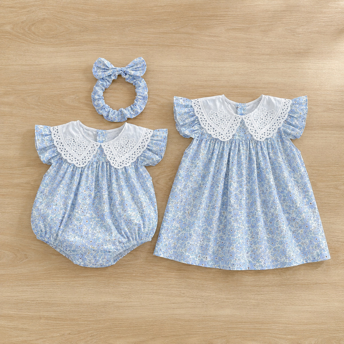 Blue floral romper and dress arranged separately on a light oak table