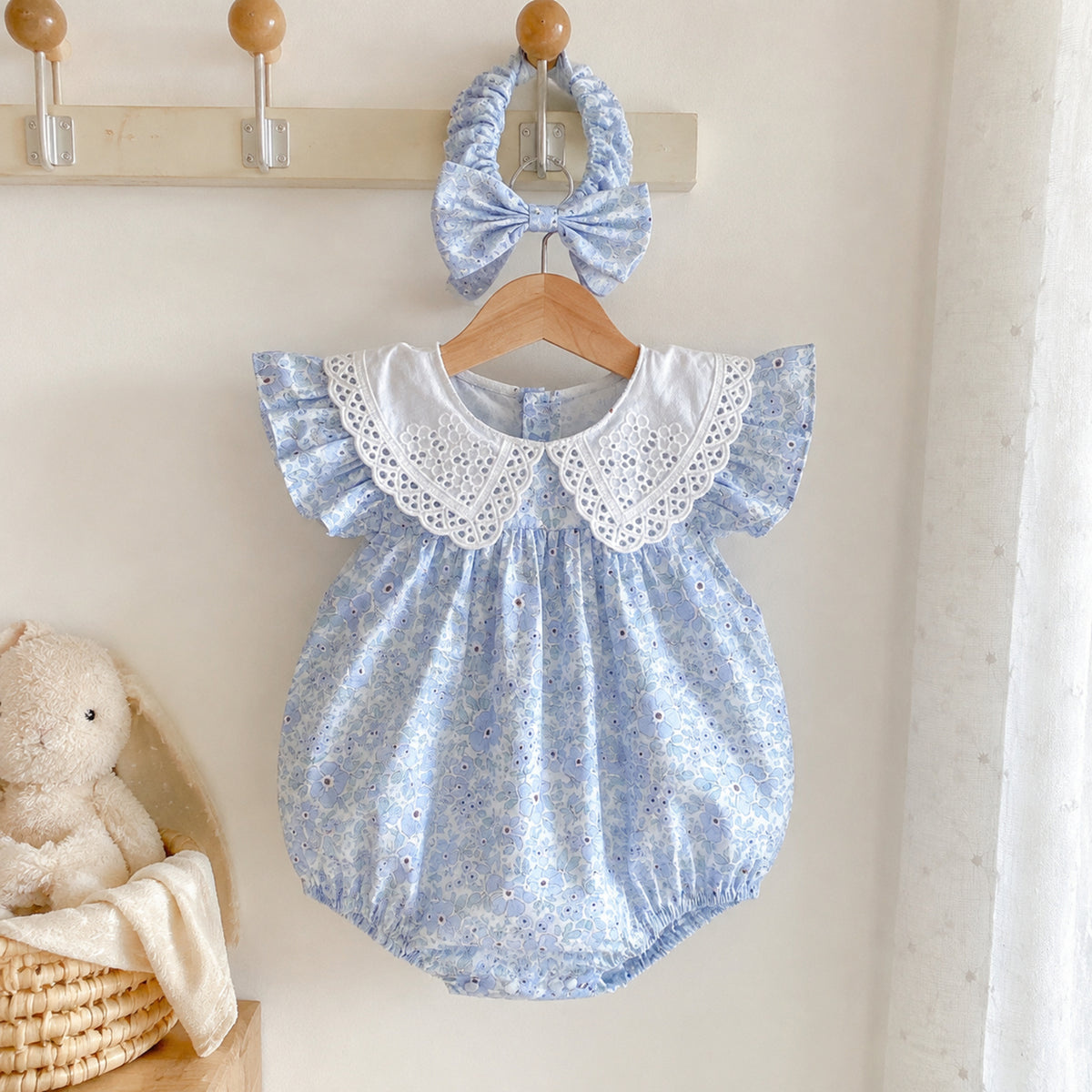 Blue floral baby romper hanging with matching bow headband