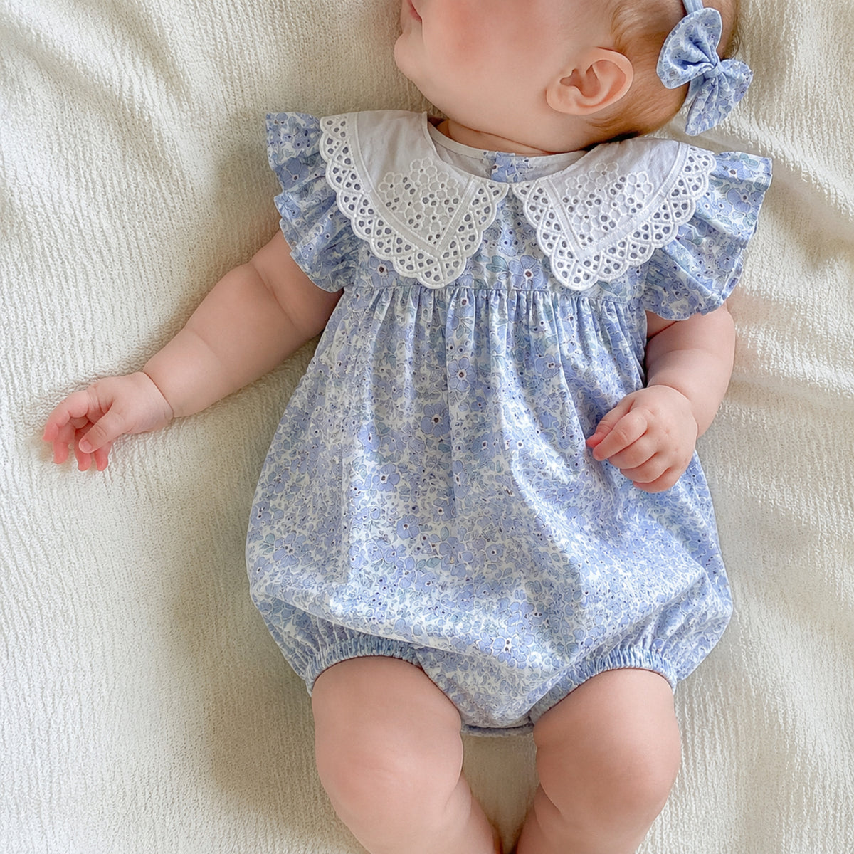 Baby wearing powder-blue floral bubble romper