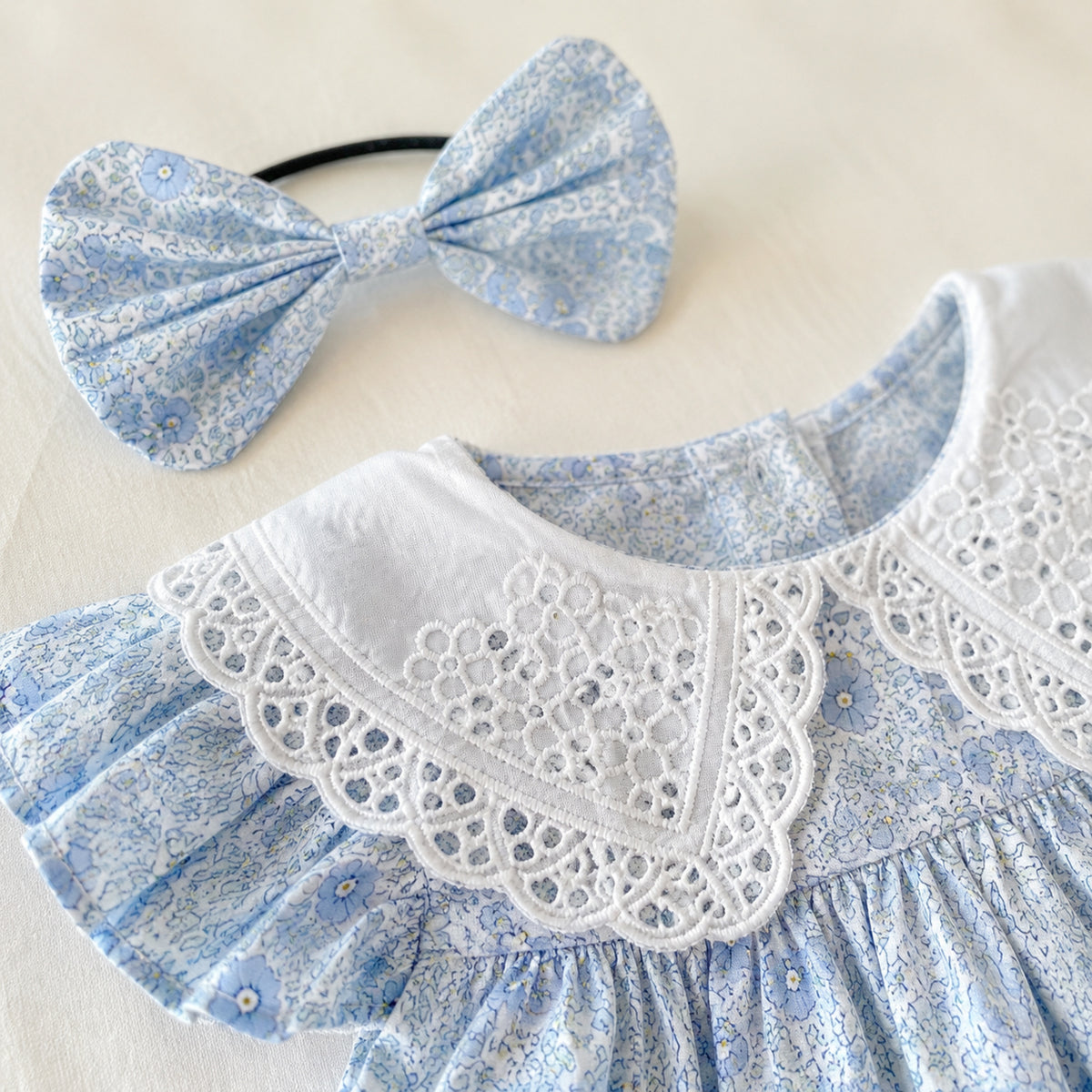 Close-up of matching blue floral bow headband and collar