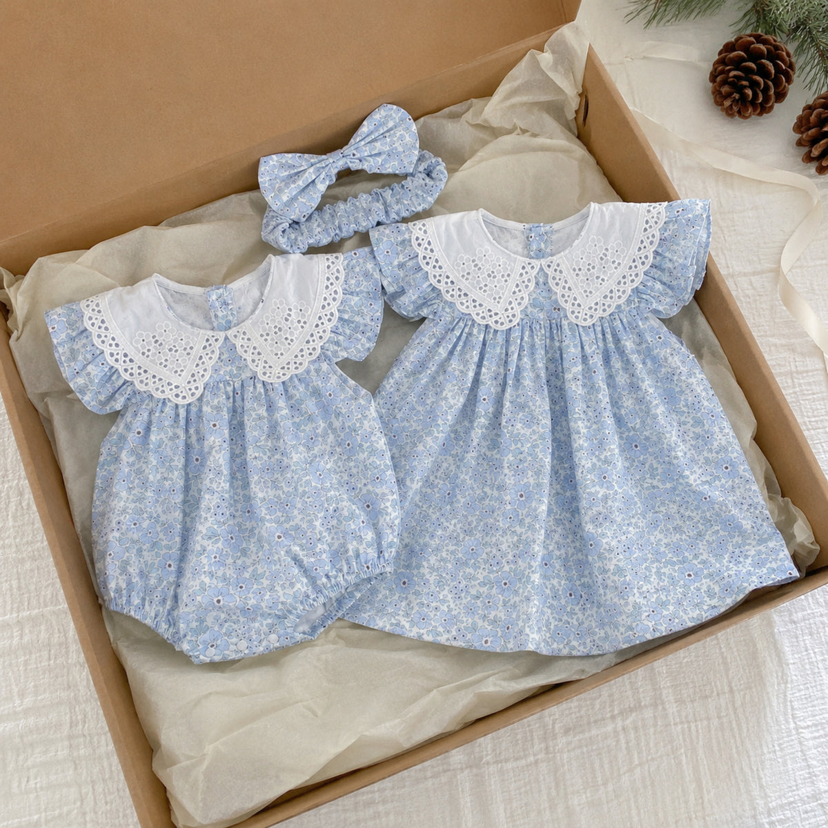 Blue floral romper and dress folded separately in a kraft box