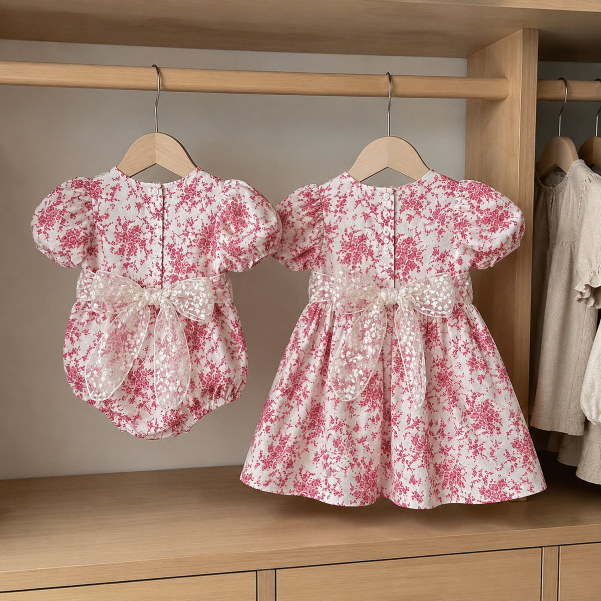 Back view of raspberry toile romper and dress on hangers