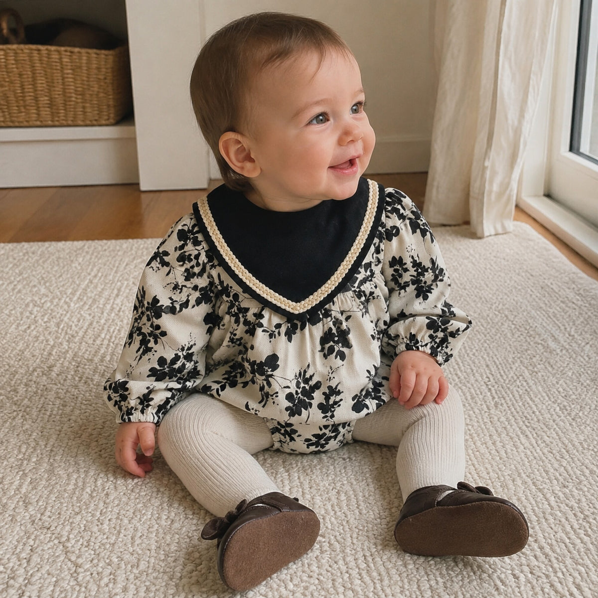 Baby wearing the black floral romper with cream tights for early autumn