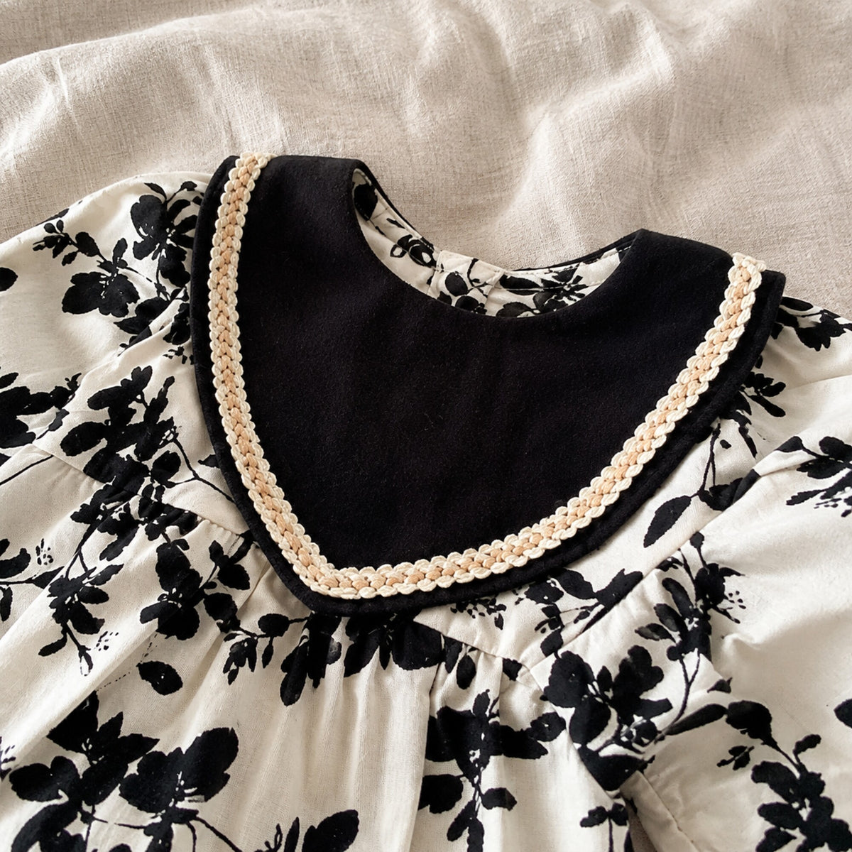 Close-up of the black sailor collar, beige braided trim and floral cotton