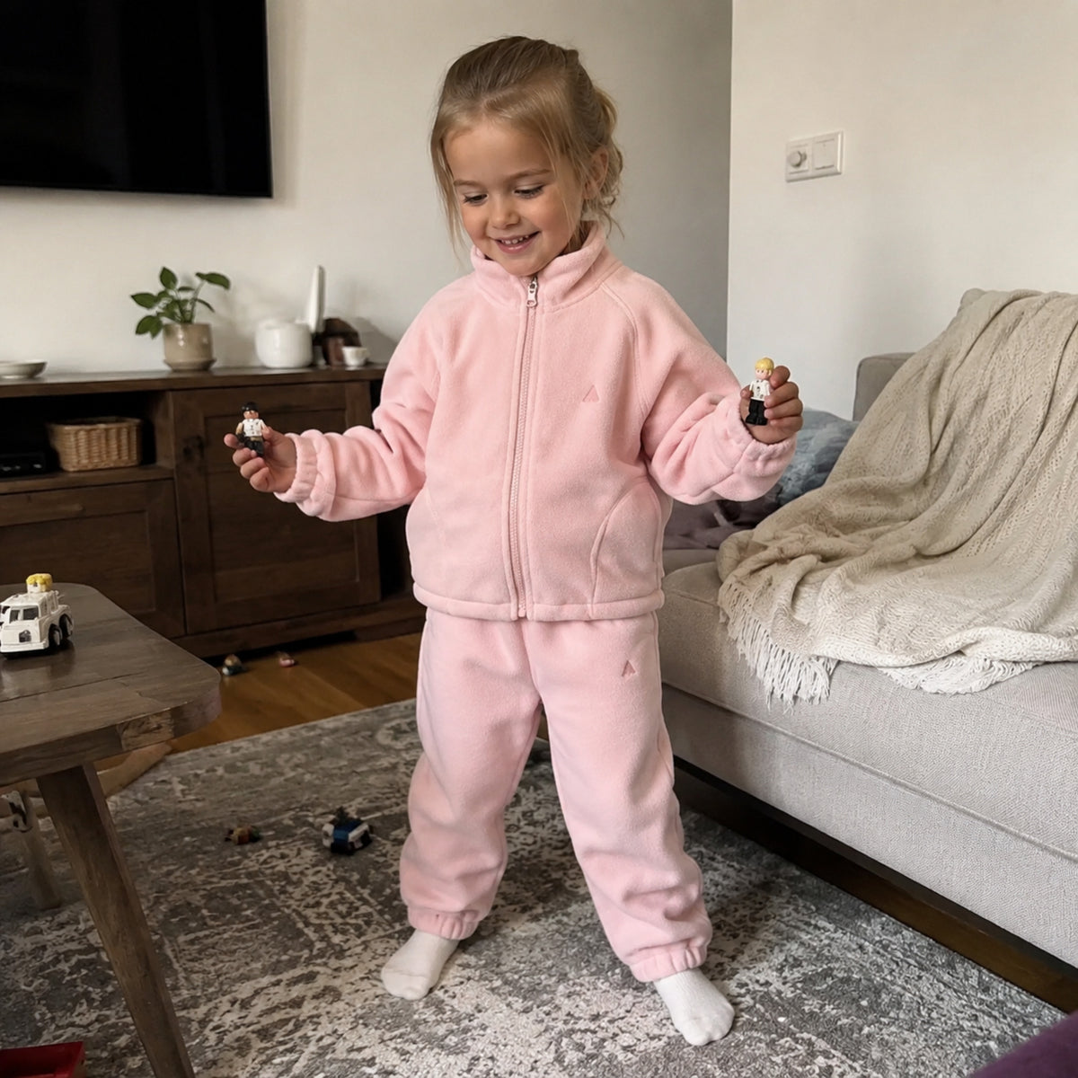 Child playing at home in rose pink fleece zip jacket and joggers