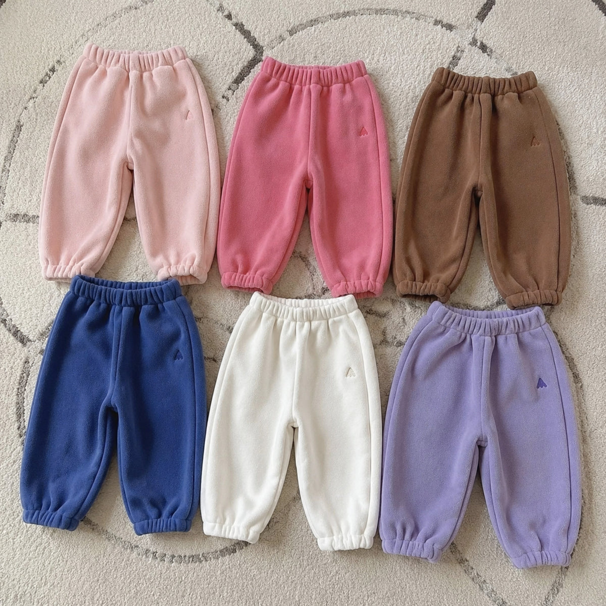 Kids fleece joggers arranged by available color on a rug