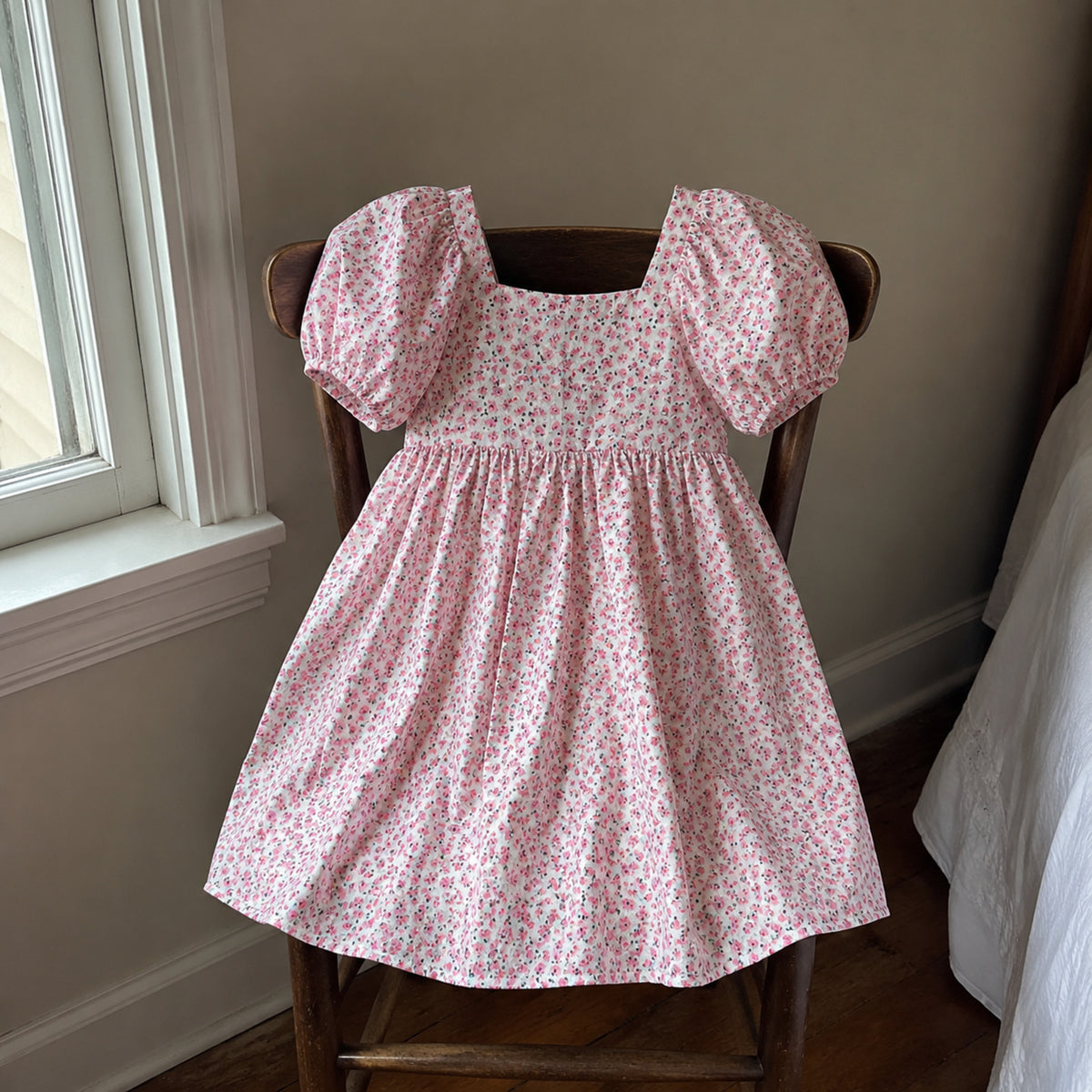 Pink floral puff sleeve girls dress hanging in a natural home setting