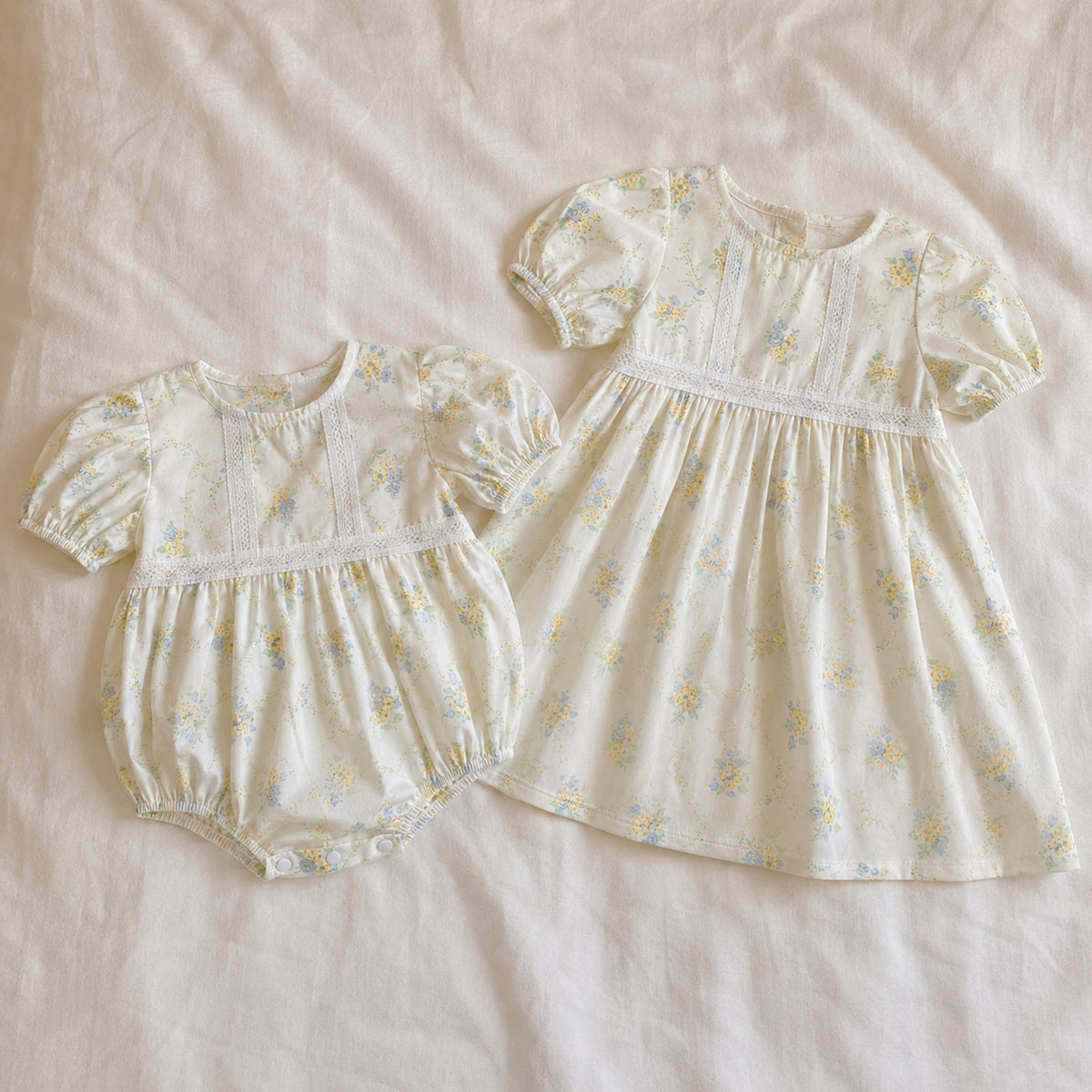 Ivory floral baby romper and toddler dress laid flat