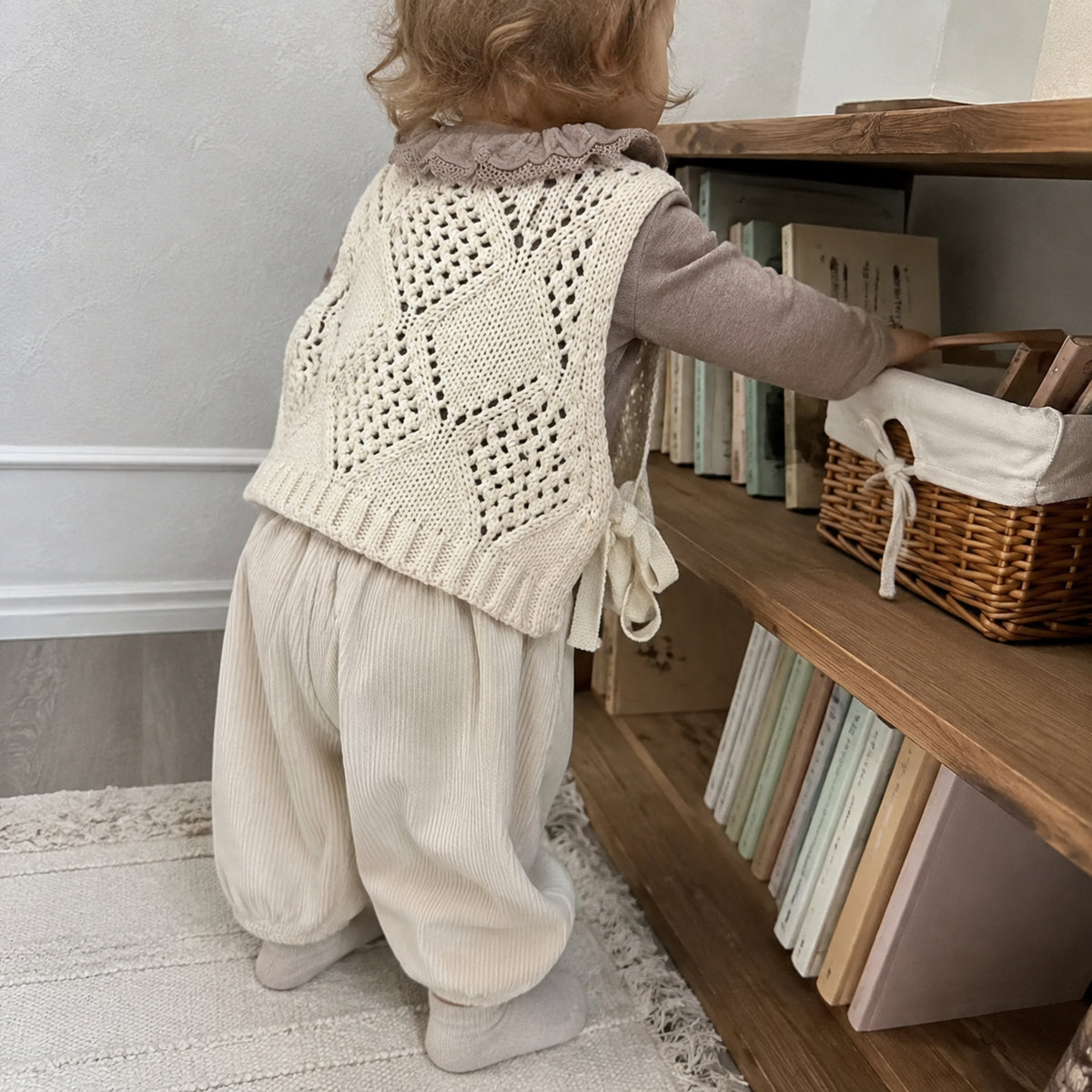 Back view of toddler wearing the cream side-tie vest and corduroy pants outfit