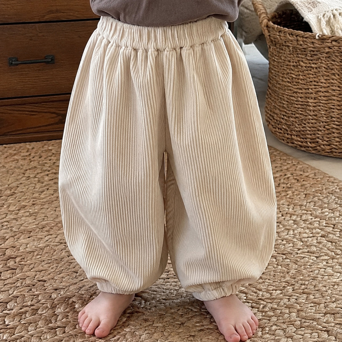 Close-up of the cream fine-corduroy balloon pants with elastic waist and gathered cuffs