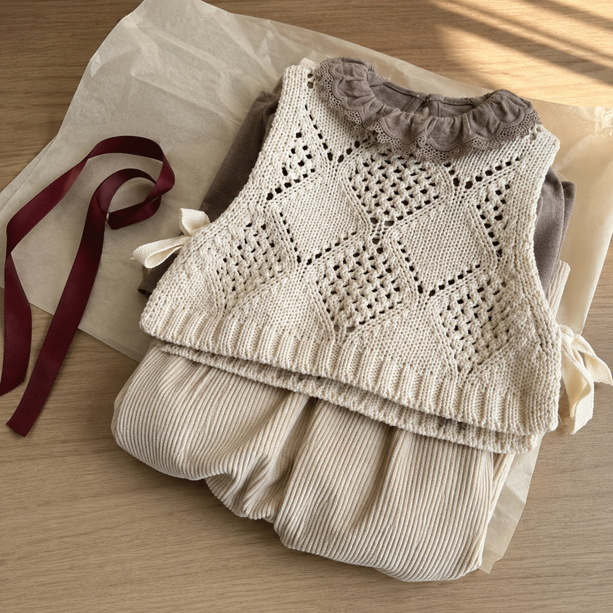 Neutral knit vest, ruffle top and corduroy pants folded for a thoughtful Q4 gift