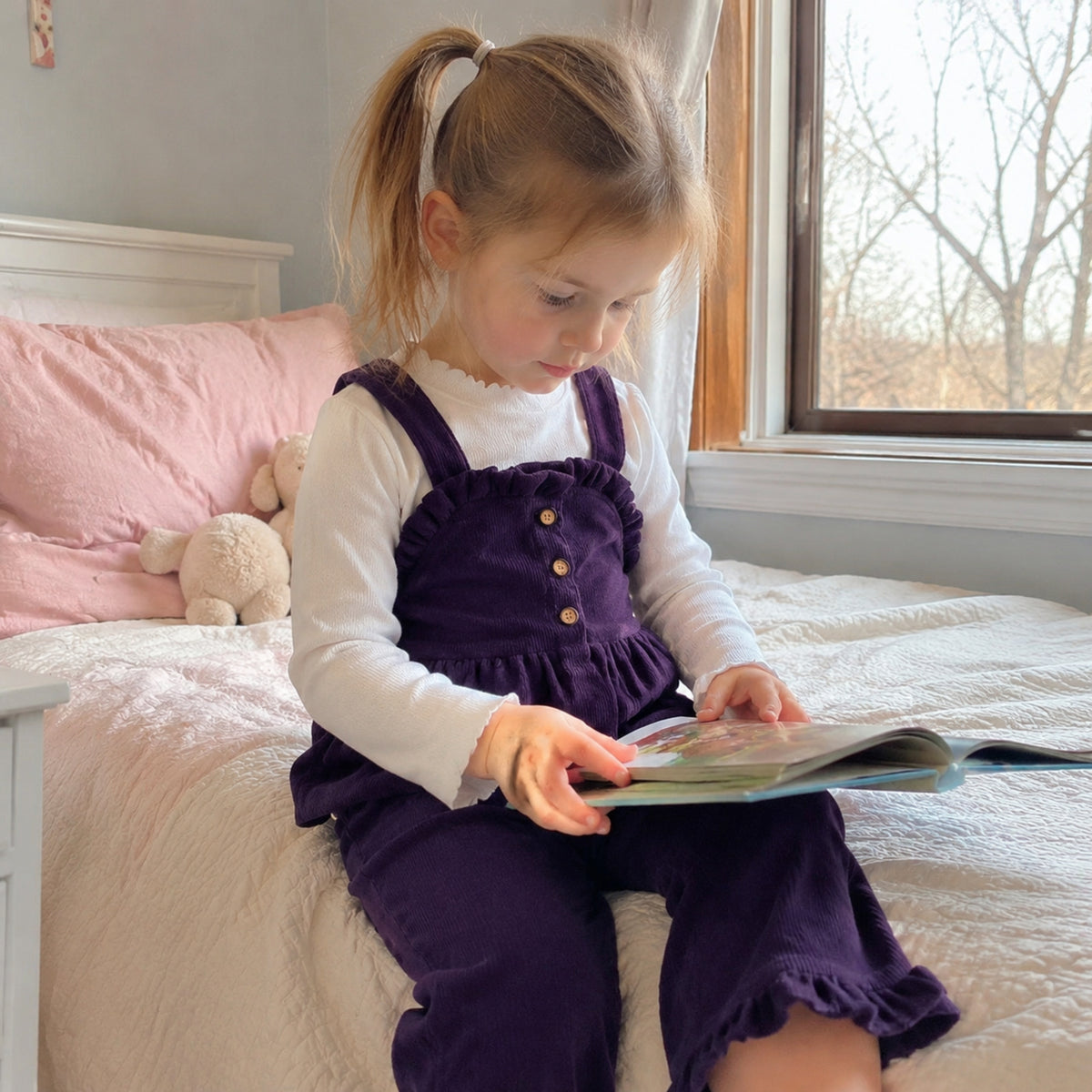 Girl reading in deep purple button-front pinafore and pants set