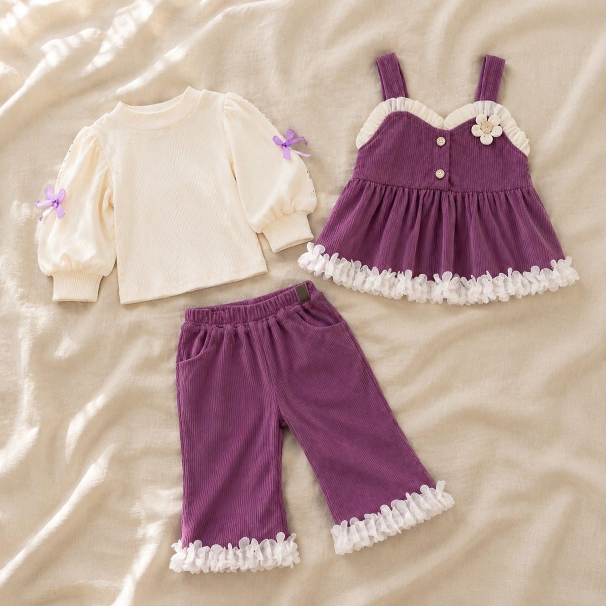 Plum ruffle top, pinafore and pants displayed as three coordinated pieces