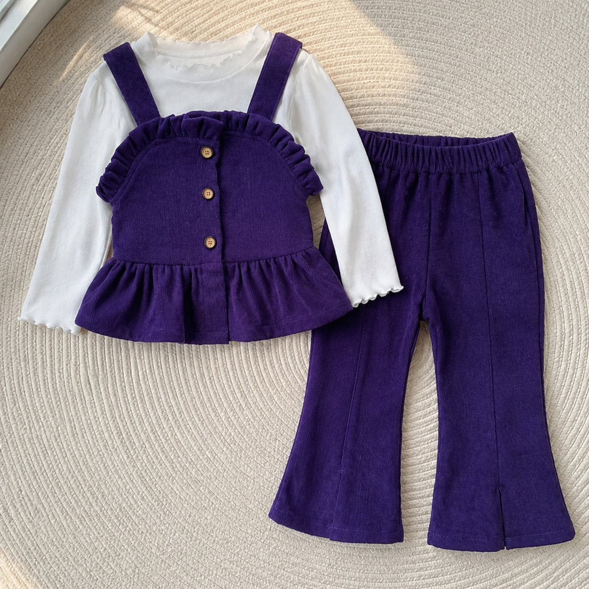 Deep purple button-front top, pinafore and pants set on a woven rug