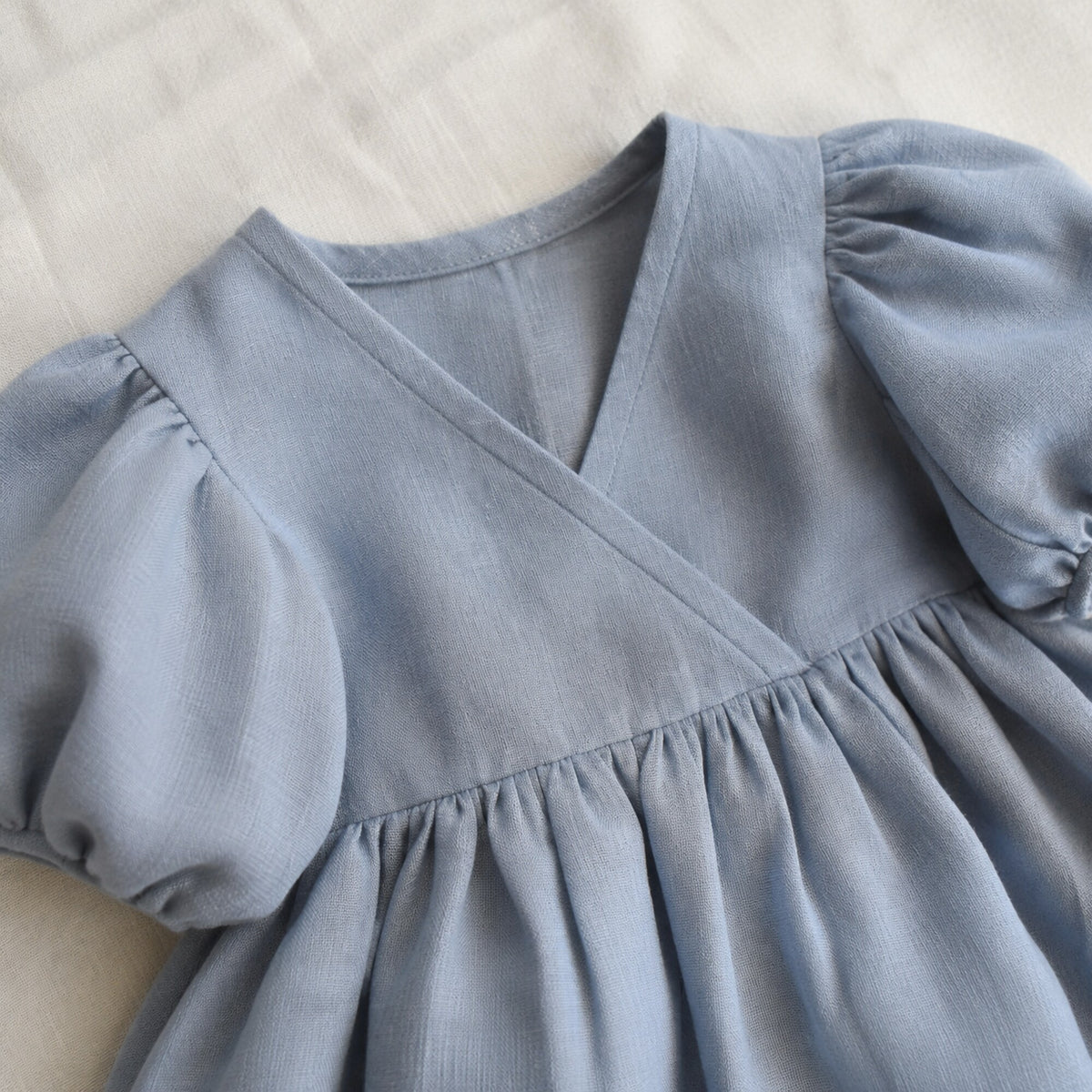 Close-up of the crossover V bodice and gathered waist on the blue dress