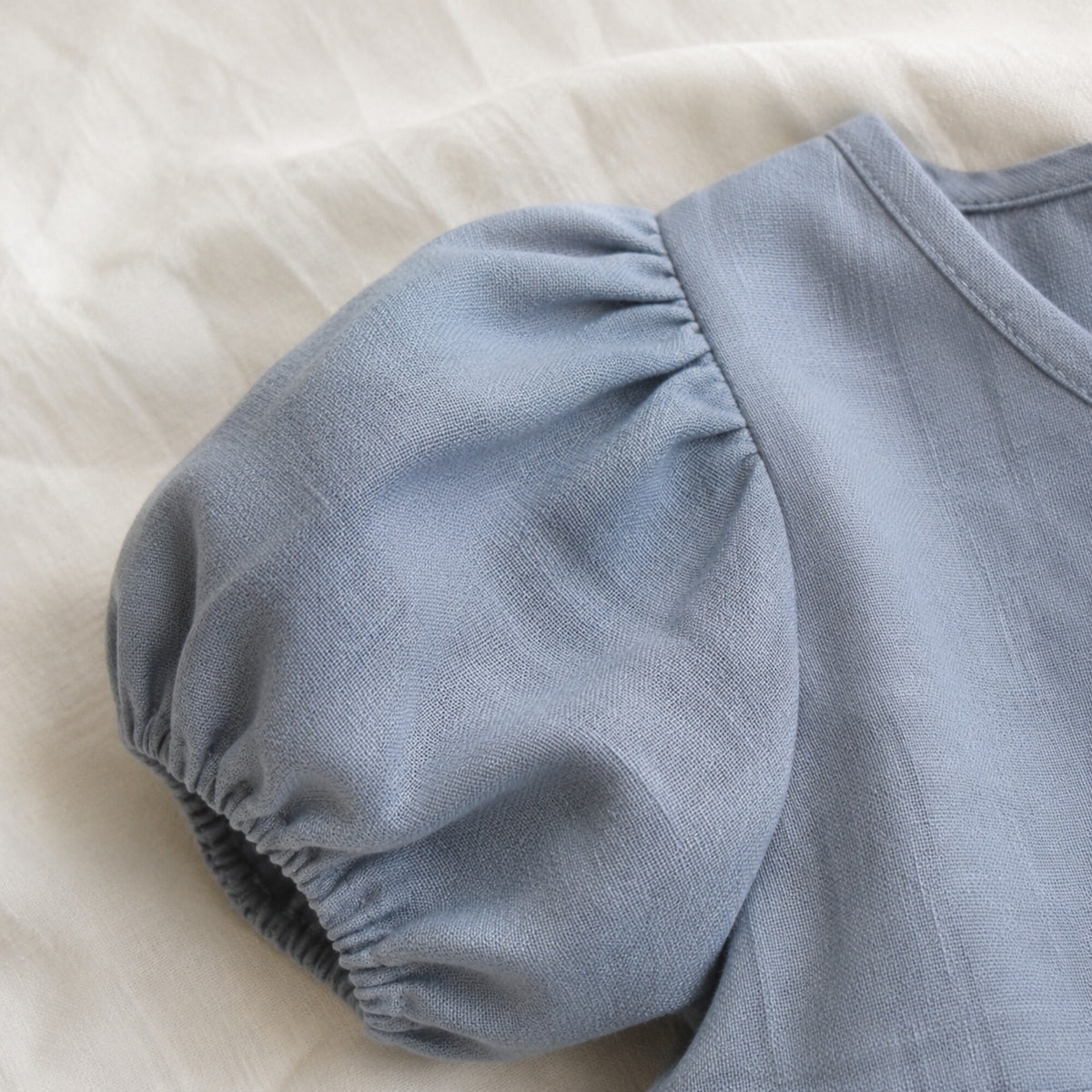 Close-up of the short puff sleeve and textured blue linen fabric
