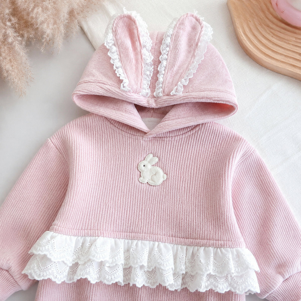 Close-up of bunny-ear pullover hood, ribbed fabric and lace peplum