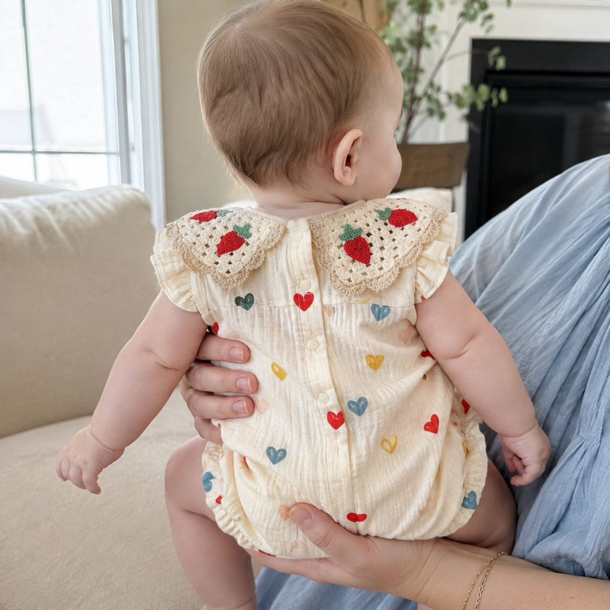 Parent holding baby in cream heart-print bubble romper
