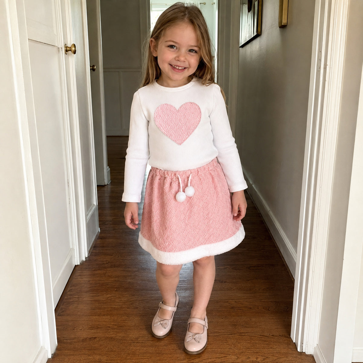 Girl wearing pink heart top and skirt set at home
