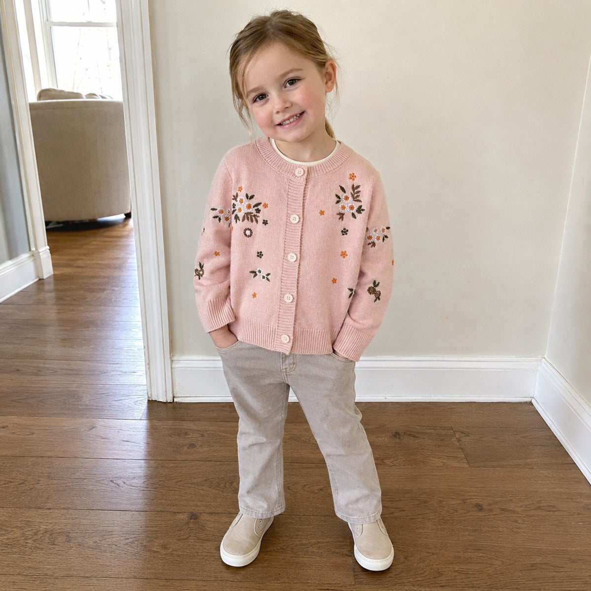 Girl wearing blush pink embroidered cardigan at home