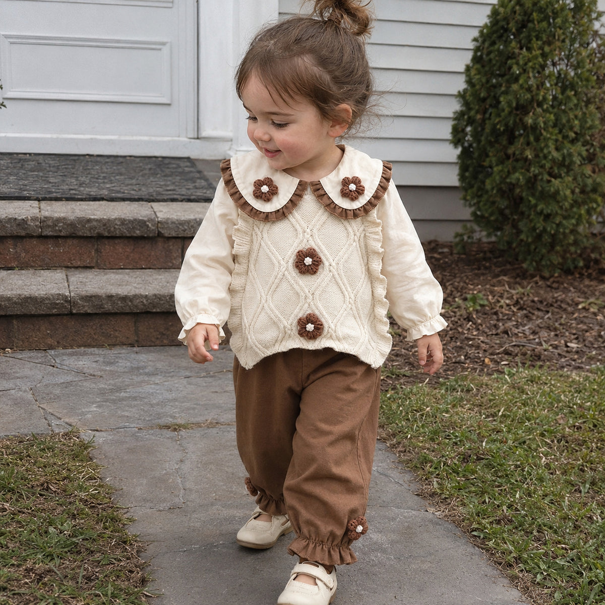 Toddler girl wearing warm ivory sweater vest outfit outdoors