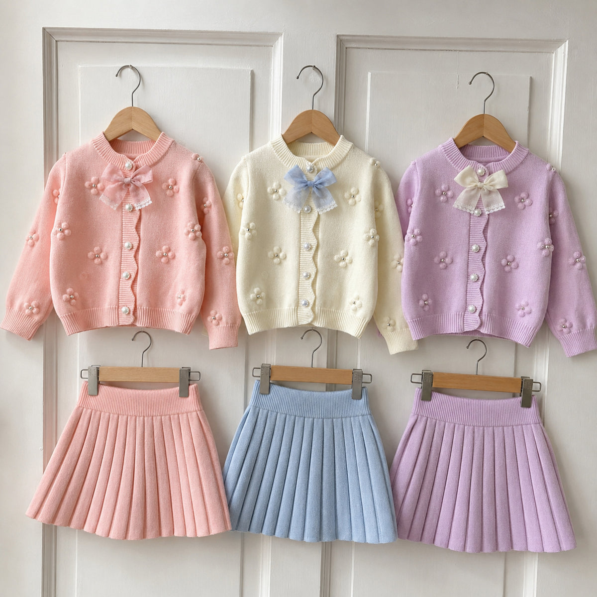 Three cardigans and matching pleated skirts hanging